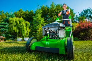 professional gardener mowing a lawn using a green lawn mower
