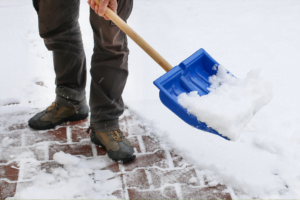 Man removing snow from walkway using a blue shovel