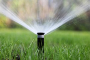 Automatic Sprinkler spraying water on green meadow
